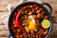 Sizzling spicy pork sisig with egg and lime